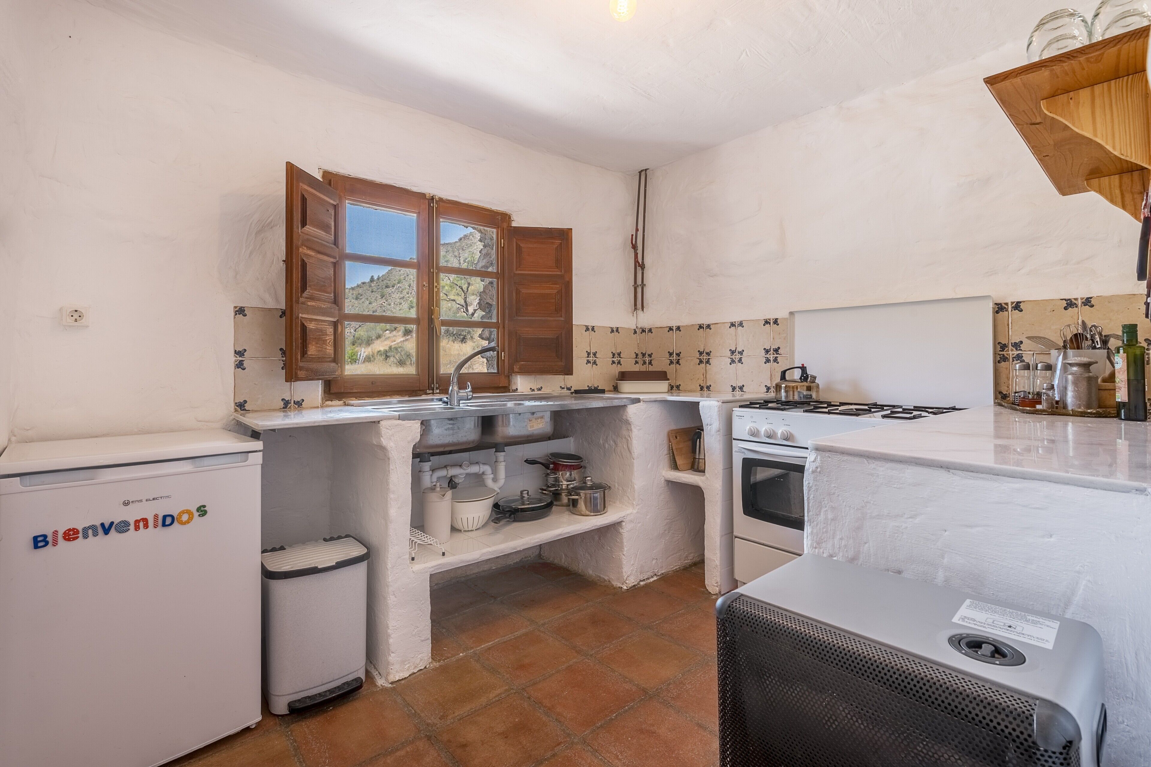 A compact kitchen with a window, a washing machine, and a stove.