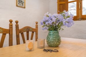 A wooden dining table with a vase of purple flowers, a candle, and a small figurine. - Apartment 'Lola' with Mountain Views, Private Terrace and Wi-Fi (Torvizcón)