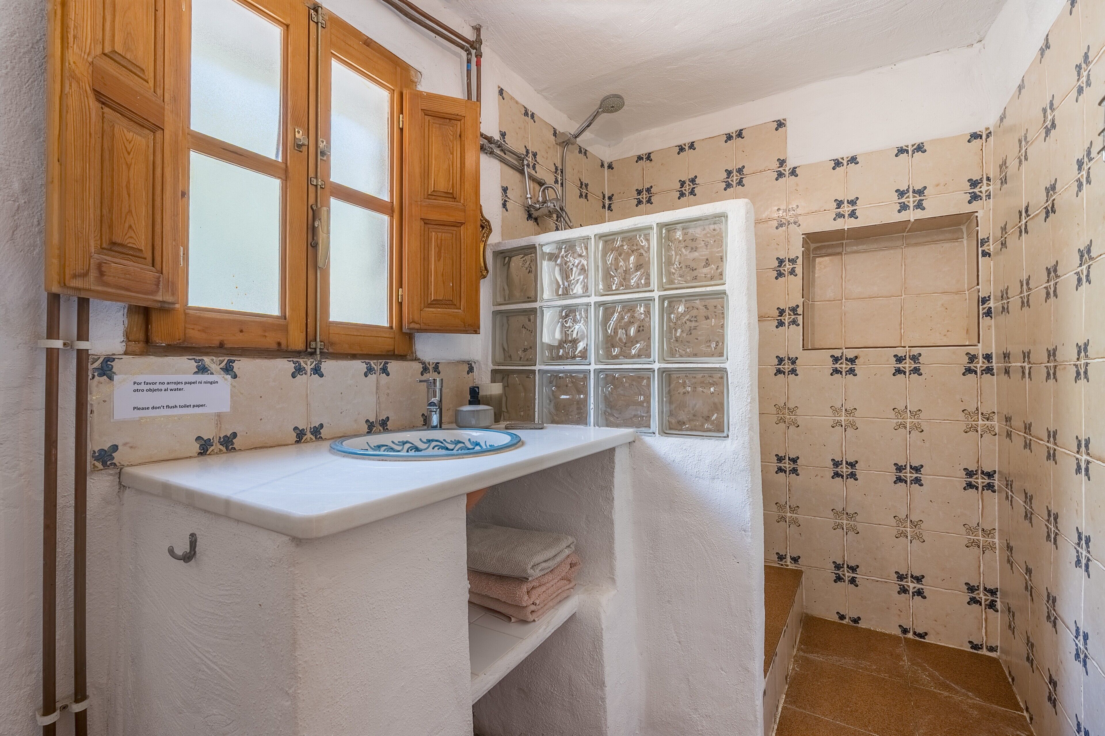 Un bany amb armaris de fusta, un lavabo i una dutxa.
