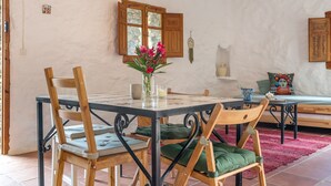 A dining area with a table, chairs, a vase with flowers, and wooden cabinets.