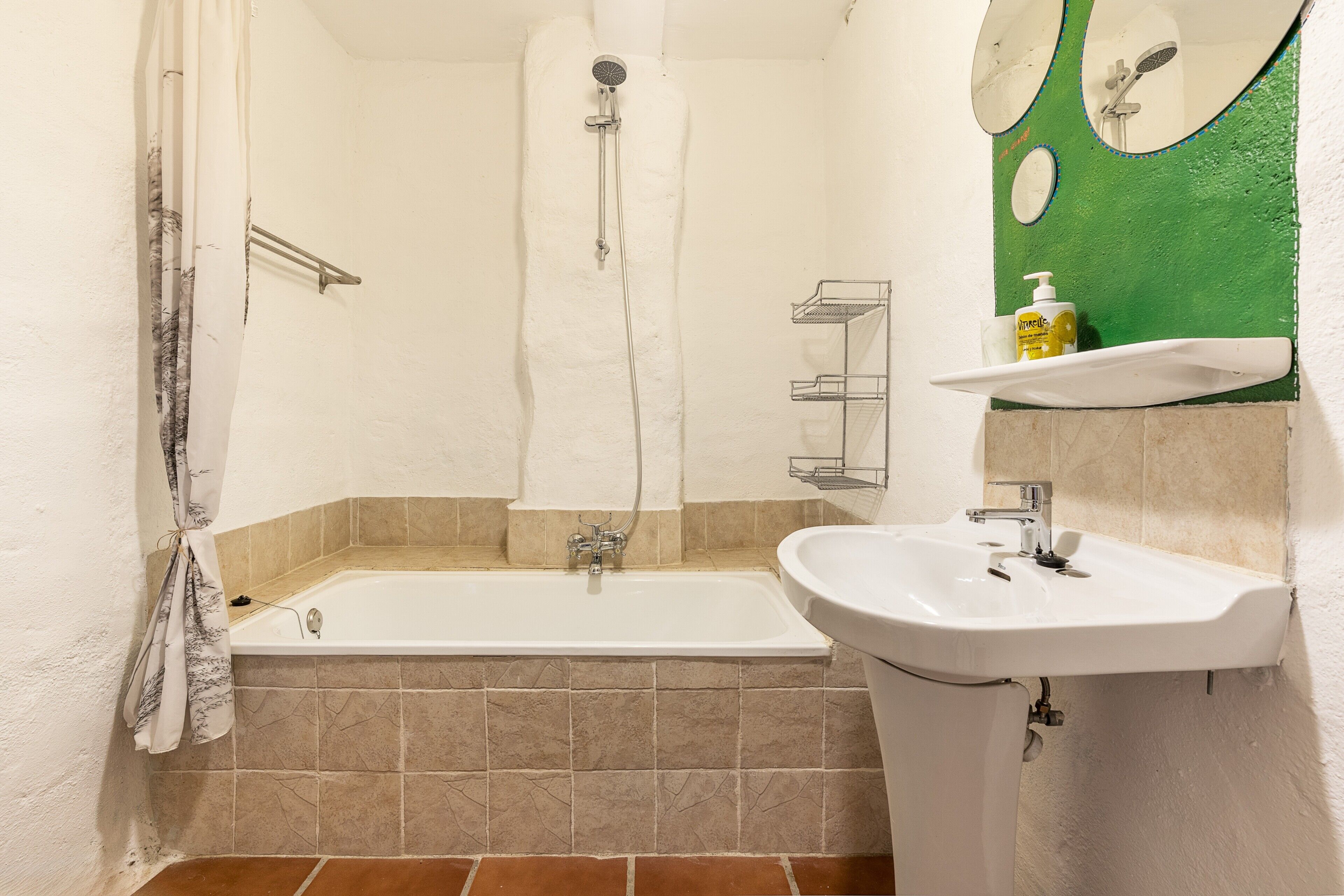 Un baño con bañera, lavamanos, ducha y espejo.