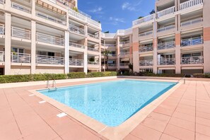 A multi-story hotel with a central swimming pool surrounded by a tiled deck. - Apt sea view with swimming pool, Golfe-Juan, France (Golfe-Juan)