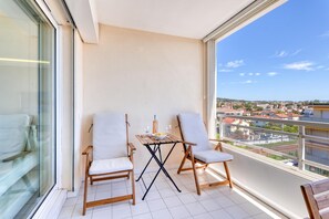 A balcony with two chairs, a small table, and a view of a cityscape. - Apt sea view with swimming pool, Golfe-Juan, France (Golfe-Juan)