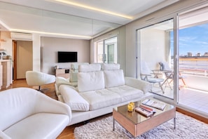 A modern living room with a sofa, armchairs, a coffee table, and a TV.