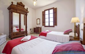 Ein Hotelzimmer mit zwei Betten, einem großen Spiegel, einem Schminktisch, einem Fenster und einer Lampe.