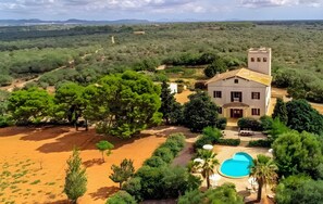 Une maison avec une piscine, entourée d’arbres et située au milieu d’un paysage désertique.