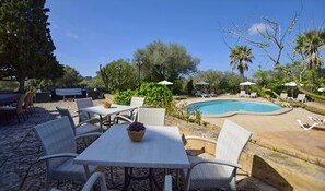 Un espace aménagé au bord de la piscine, avec des chaises longues, une table et un barbecue.