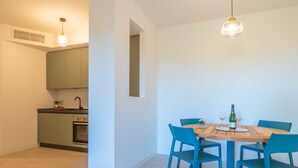 Una cocina moderna con horno empotrado y comedor con mesa de madera y sillas azules.