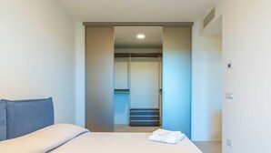 Una habitación de hotel moderna con una cama, un armario y un baño visible a través de una puerta corrediza.