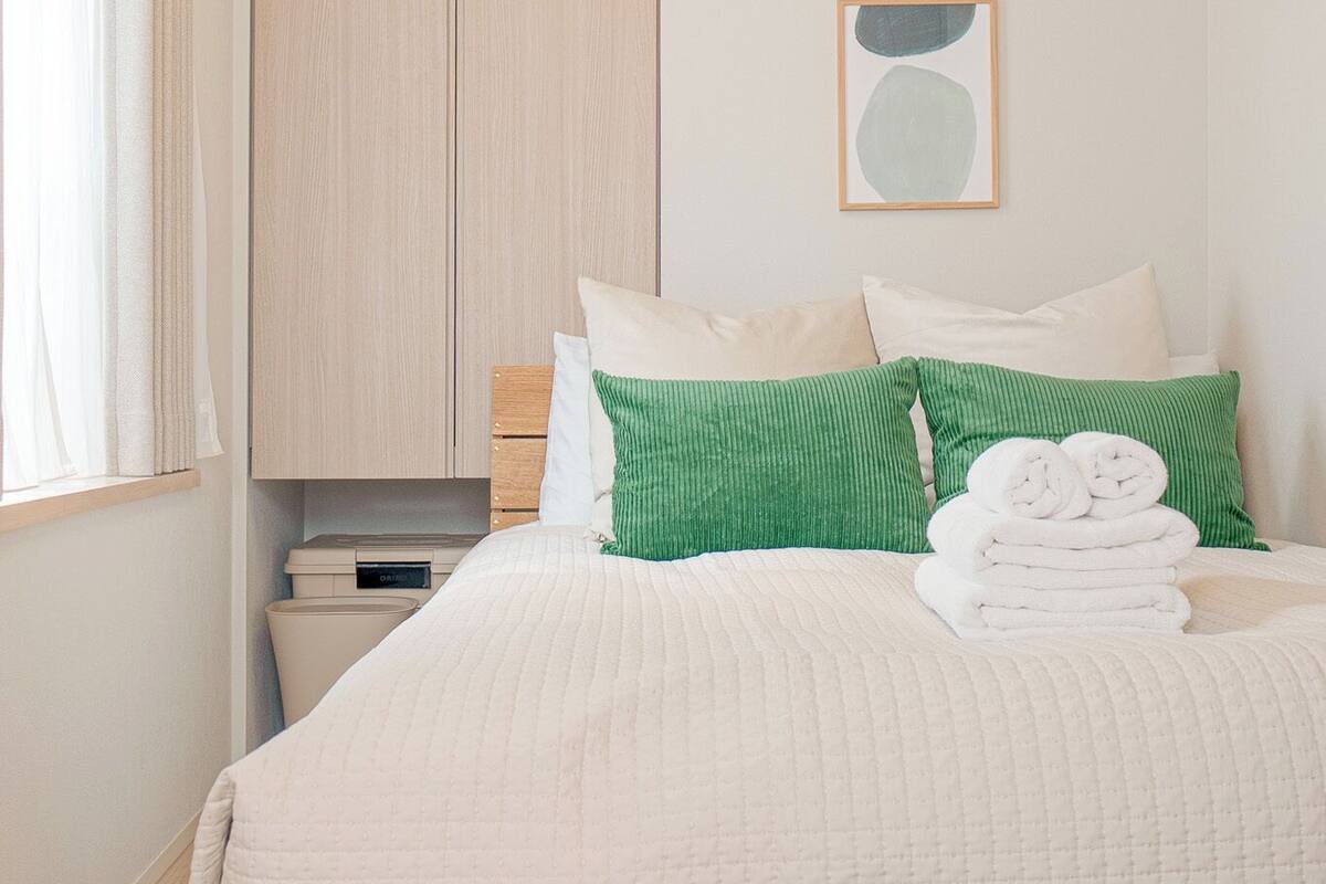 A neatly arranged bedroom with a bed, pillows, and a bedside table.