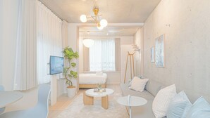 Un salon moderne avec un canapé, une table basse, un téléviseur et une plante.