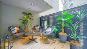Un espace extérieur moderne aménagé avec des chaises en osier, une table ronde et des plantes en pot.