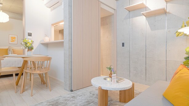 Un salon moderne avec une table basse ronde, un canapé et un coin repas comprenant des chaises en bois et une petite table.