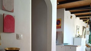 A modern kitchen with a large white cabinet, a wooden table with a bowl, and a white trash bin. - Penthouse in Ciudad Vieja (Cordoba)