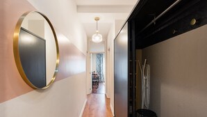 A hallway with a round mirror, a hanging light fixture, and a door leading to another room.