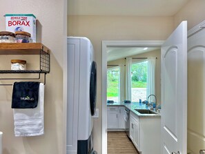 A modern kitchen with white cabinets, a built-in oven, and a window overlooking a garden.