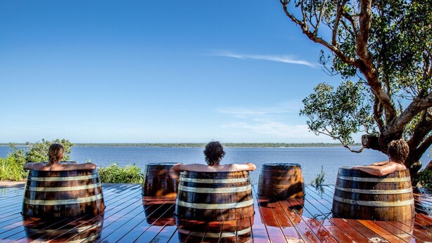 A wooden deck with four barrels and a tree. - Blackwood at Boardwalk Villas Metung (Metung)