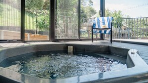 A hot tub with a view of a fenced garden and a chair with a striped towel. - Blackwood at Boardwalk Villas Metung (Metung)