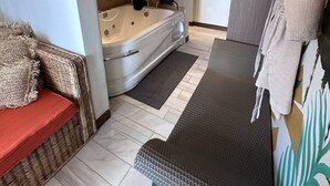 Un bagno moderno con una vasca, una zona doccia e un angolo relax con una panca e dei cuscini.