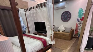 Una camera da letto con un letto a baldacchino, una televisione, un divano e un elemento decorativo a parete.