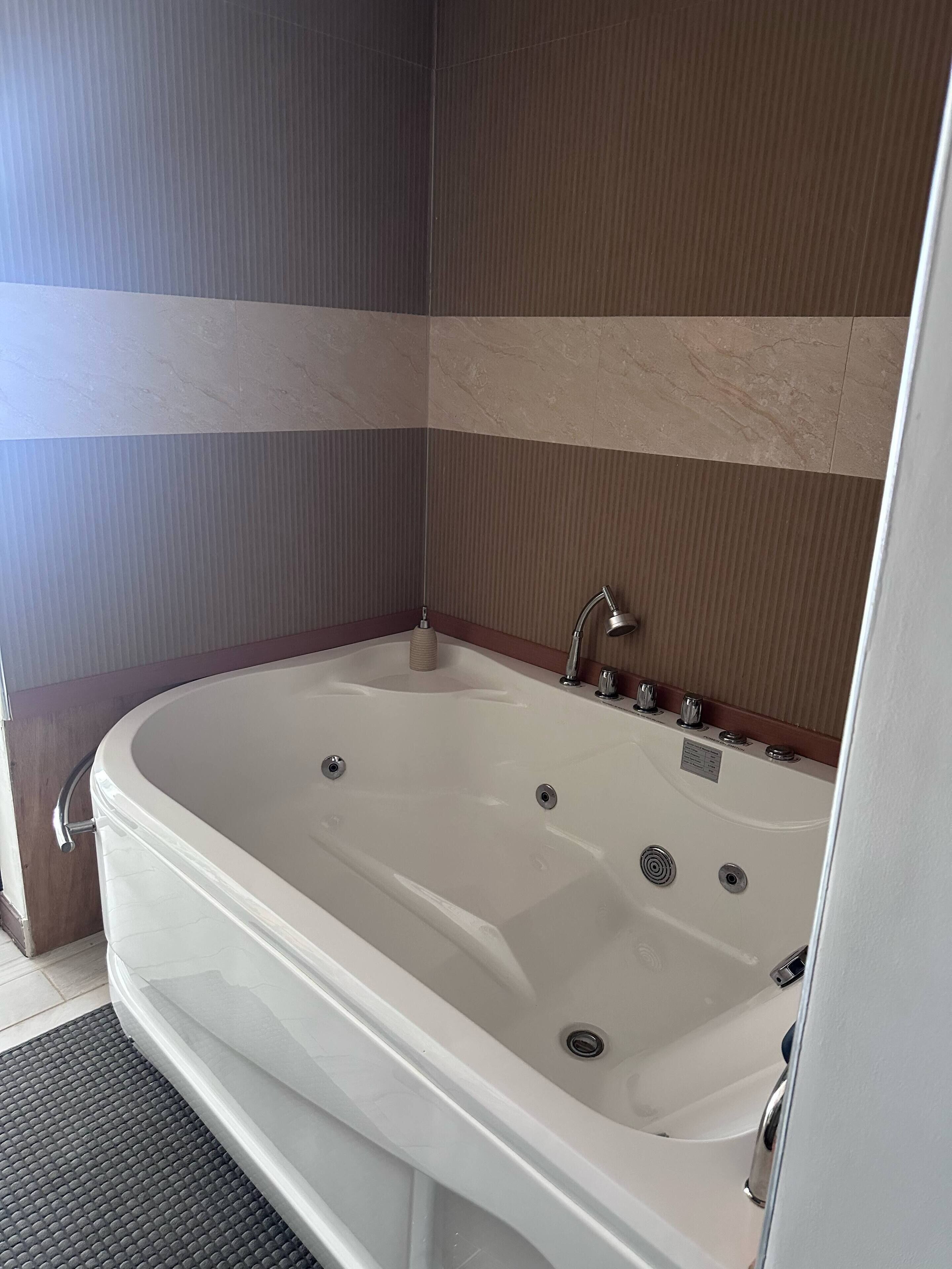 A modern bathroom with a freestanding bathtub, a showerhead, and a control panel.