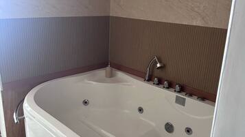A modern bathroom with a freestanding bathtub, a showerhead, and a control panel.