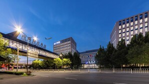A modern urban street scene with a clear sky, a pedestrian overpass, and buildings with commercial signage. - Beijing CSN Pearl Hotel (Langfang)