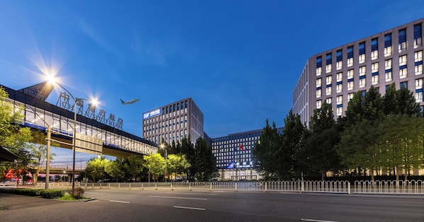 A modern urban street scene with a clear sky, a pedestrian overpass, and buildings with commercial signage. - Beijing CSN Pearl Hotel (Langfang)