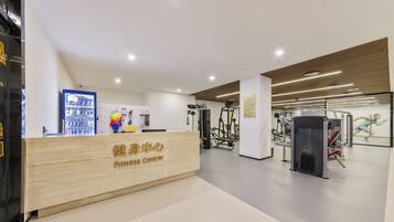 Un gimnasio con mostrador de recepción, máquinas de ejercicio y un mural temático de acondicionamiento físico.