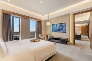 Una habitació d'hotel amb un llit gran, televisió, escriptori i vista a la ciutat.