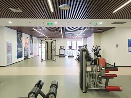 Un gimnasio con equipo de ejercicio, un muro con espejos y un techo con diseño a rayas.
