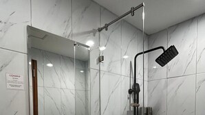 A bathroom with a white sink, a mirror, a shower with a handheld showerhead, and a 'CONSERVE' sign. - d'primahotel Harmoni Jakarta-Hayam Wuruk (Jakarta)
