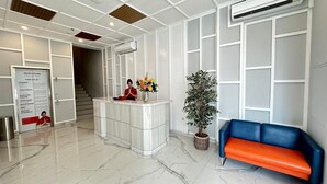 A reception area with a marble floor, a reception desk, a blue and orange sofa, and a potted plant. - d'primahotel Harmoni Jakarta-Hayam Wuruk (Jakarta)