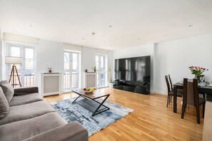 En moderne stue med sofa, sofabord, spisebord med stole, fjernsyn og pejs.