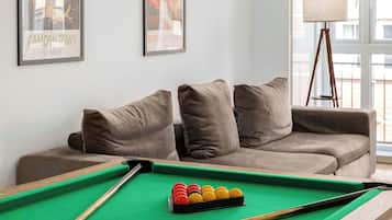 A pool table with balls, a sofa, and two framed pictures on the wall.