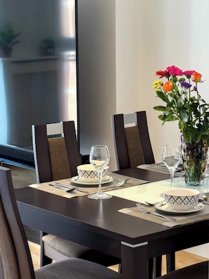 A dining table set with two wine glasses, a bowl, and a vase with flowers. - Spacious 3BR Shoreditch ApartM, 2Baths, 2 Balconies 150 SqM Sleeps Family of 6 (Greater London)