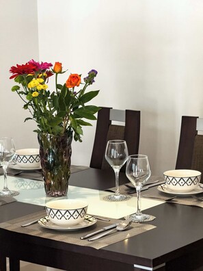 A dining table set with white bowls, clear wine glasses, and a vase with flowers. - Spacious 3BR Shoreditch ApartM, 2Baths, 2 Balconies 150 SqM Sleeps Family of 6 (Greater London)