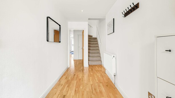 A hallway with wooden flooring, a white radiator, a coat rack, and a staircase leading to another room. - Spacious 3BR Shoreditch ApartM, 2Baths, 2 Balconies 150 SqM Sleeps Family of 6 (Greater London)