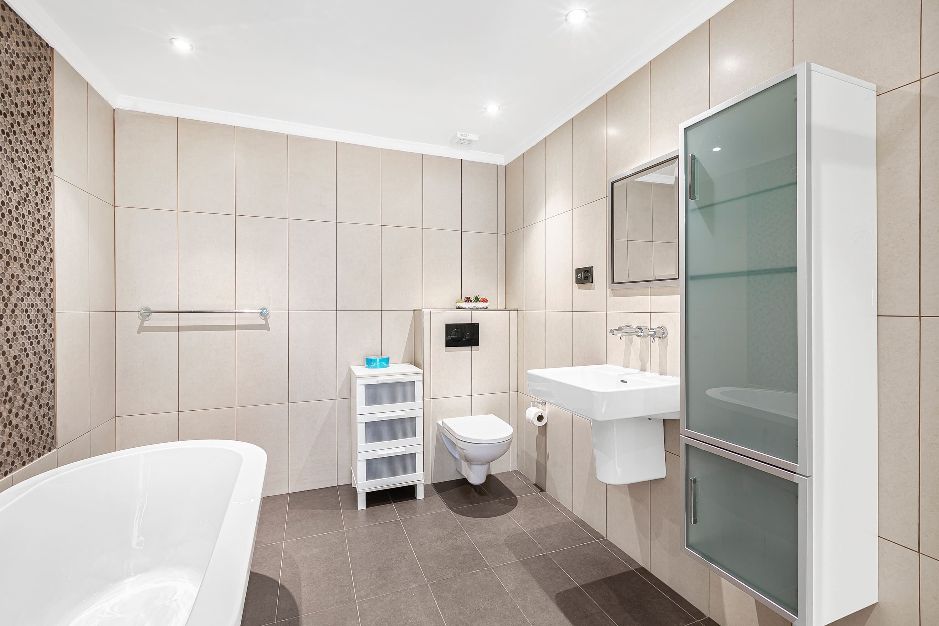 Une salle de bain moderne équipée d’une baignoire, de toilettes et d’une douche séparée par des parois en verre.