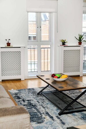 Un salon moderne avec une table à manger, un tapis à motifs et un saladier rempli de fruits.