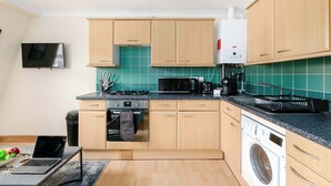 Une cuisine moderne avec des meubles en bois, un four à micro-ondes, une cuisinière et un lave-linge.