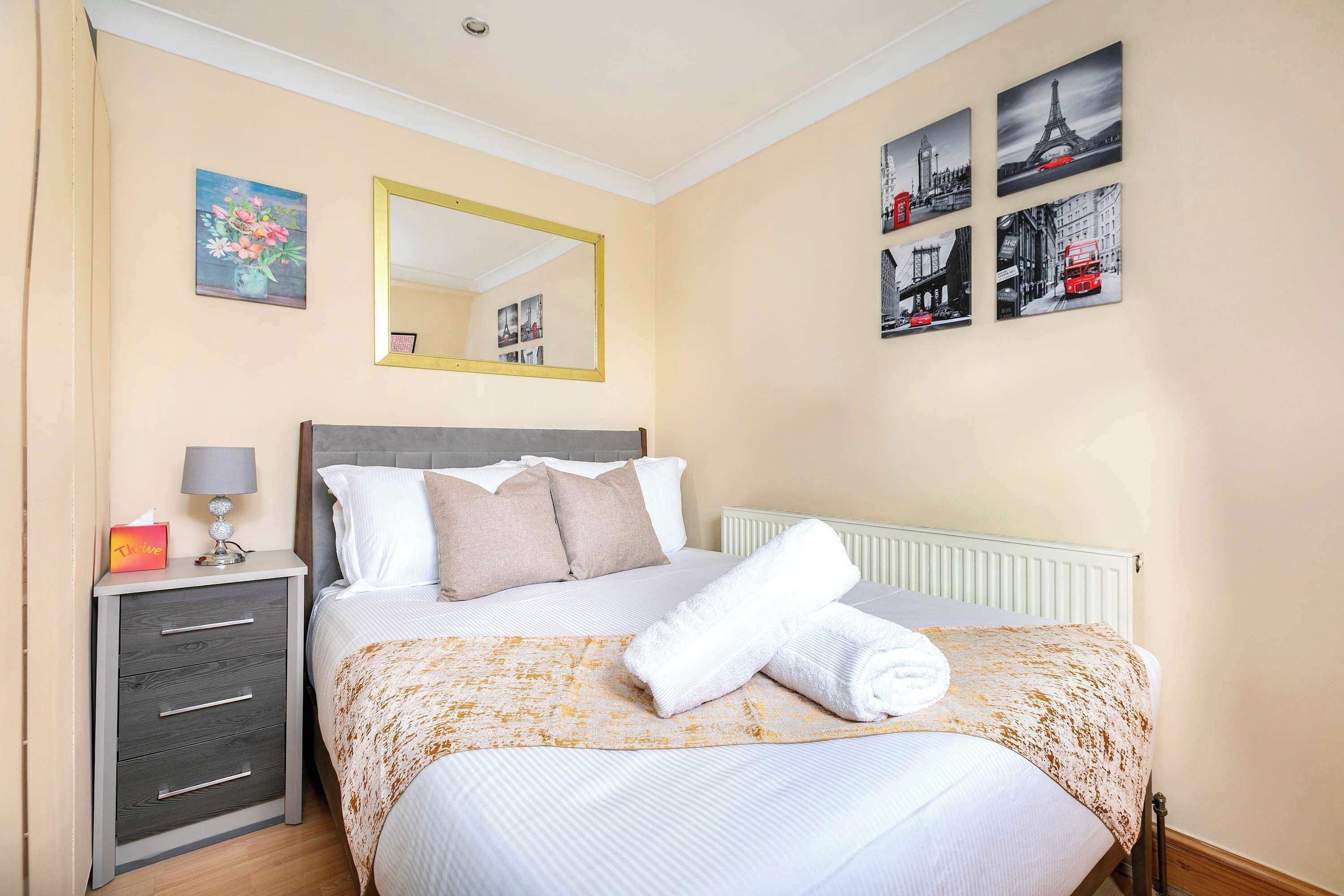 Una habitación de hotel con cama, mesita de noche, espejo y decoración en la pared.