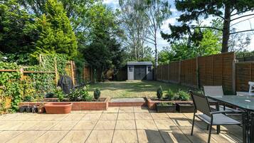 A backyard with a patio, a small shed, and a wooden fence.