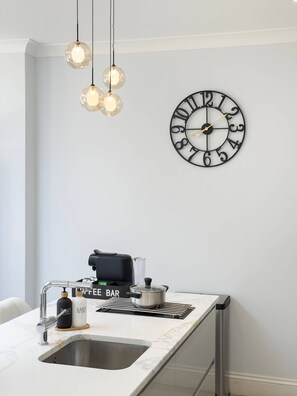 A kitchen with a sink, coffee bar, and a wall clock.