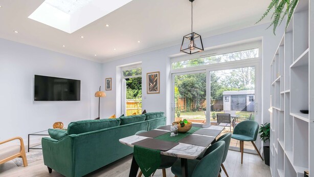Un espace de vie moderne avec un canapé vert, une table à manger et un téléviseur fixé au mur.