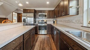 Une cuisine moderne avec des meubles en bois foncé, des appareils électroménagers en acier inoxydable et un dosseret carrelé.