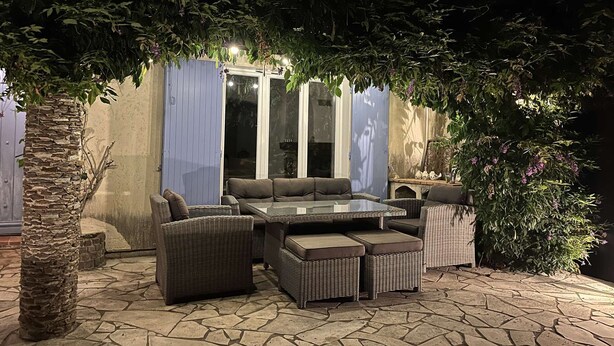 An outdoor patio area with wicker furniture, a glass-top table, and a stone floor. - VILLA FOR 6 PEOPLE, PRIVATE POOL, NEAR BEACH, SAINTE-MAXIME (STE MAXIME)