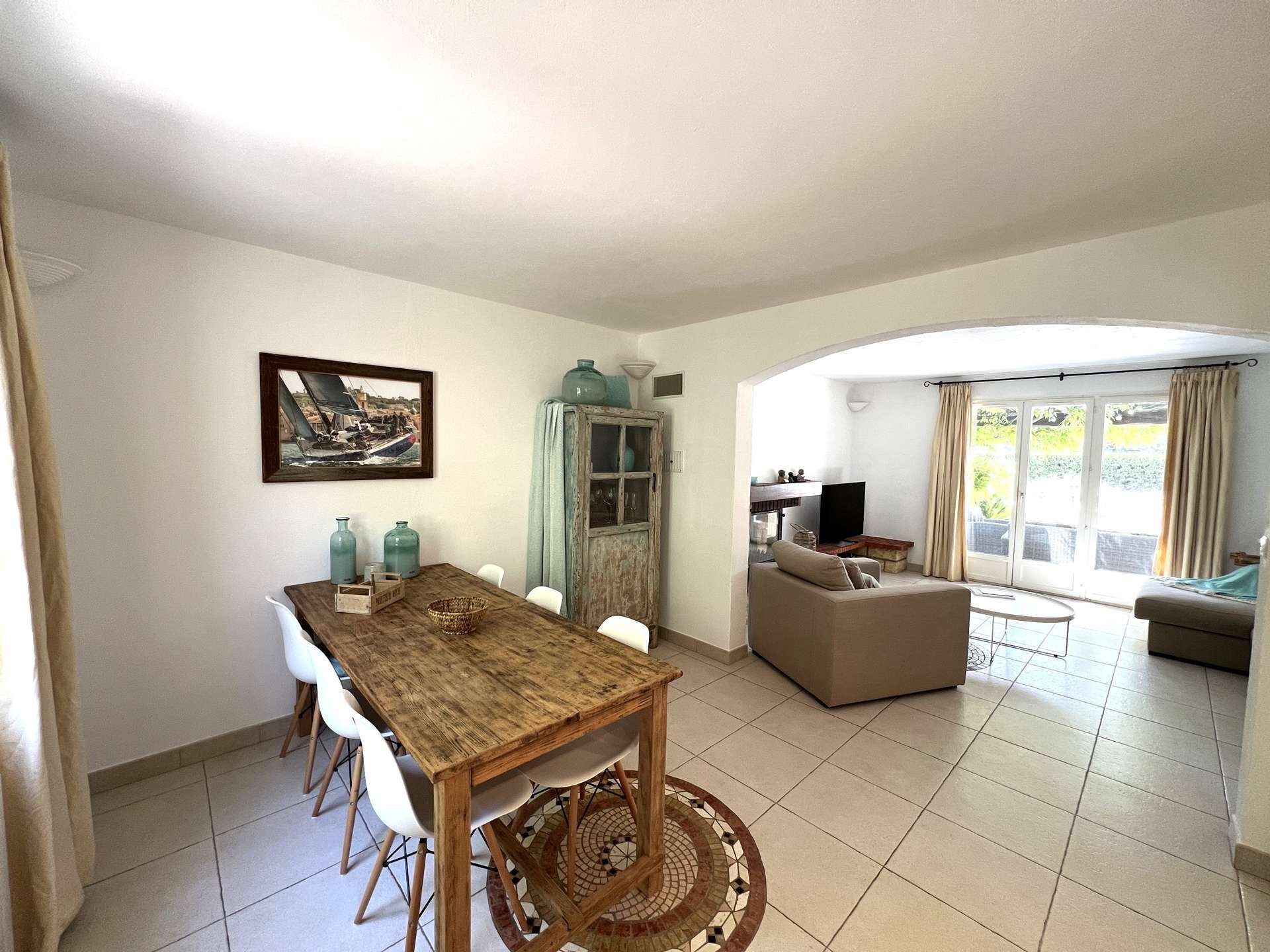 Un coin repas avec une table et des chaises en bois, un meuble avec des portes en verre et un tableau accroché au mur.