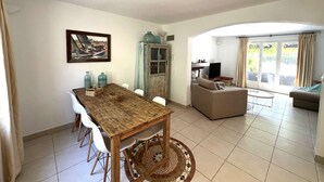 A dining area with a wooden table and chairs, a cabinet with glass doors, and a painting on the wall. - VILLA FOR 6 PEOPLE, PRIVATE POOL, NEAR BEACH, SAINTE-MAXIME (STE MAXIME)
