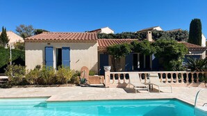 A pool area with a clear blue pool, a stone deck, and a building with a tiled roof and blue shutters. - VILLA FOR 6 PEOPLE, PRIVATE POOL, NEAR BEACH, SAINTE-MAXIME (STE MAXIME)